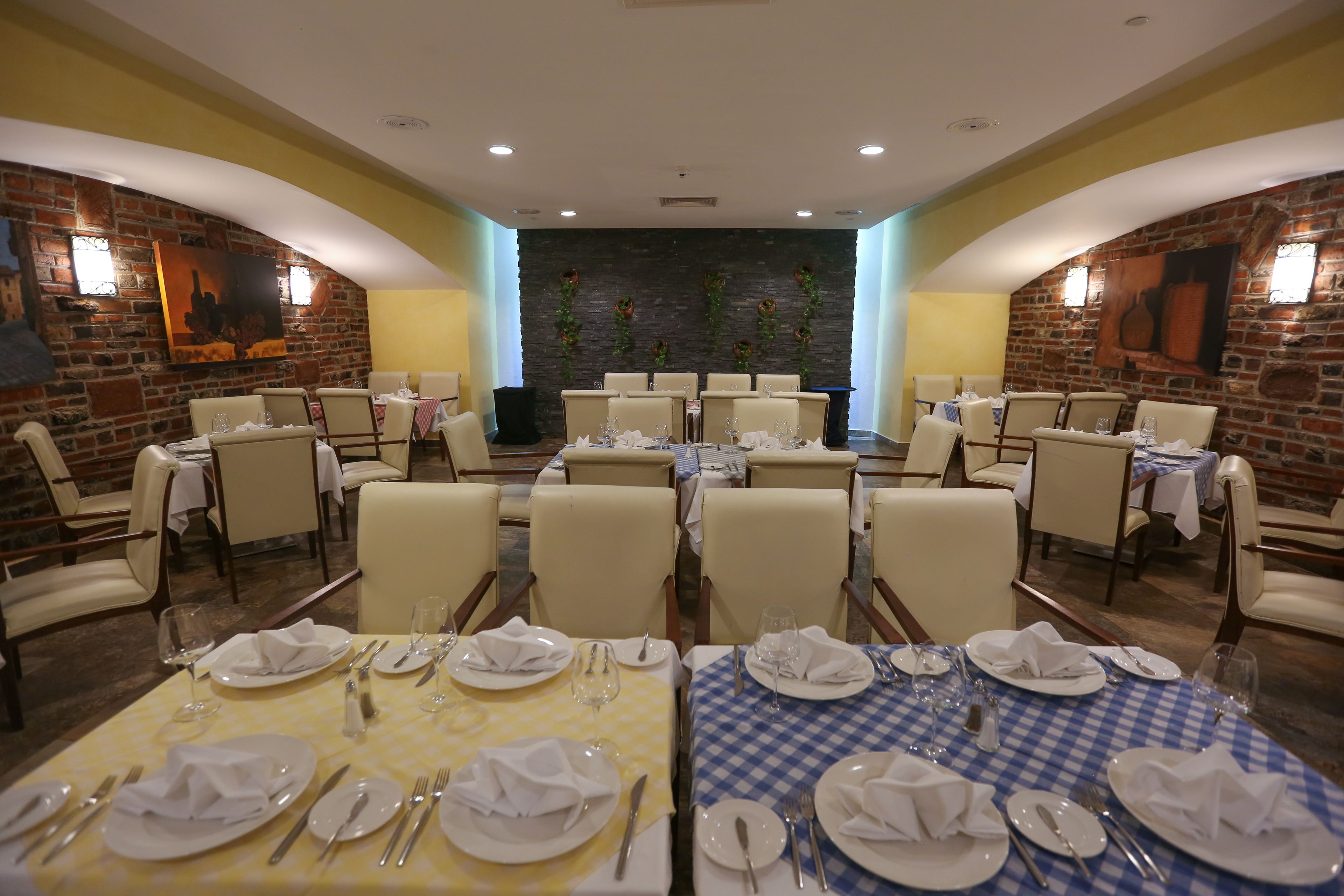 Ein Restaurant mit mehreren Tischen für Essen, das eine Backsteinwand und gerahmte Kunstwerke zeigt.