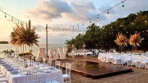Une cérémonie de mariage en plein air, avec des tables, des chaises et des guirlandes lumineuses décoratives.