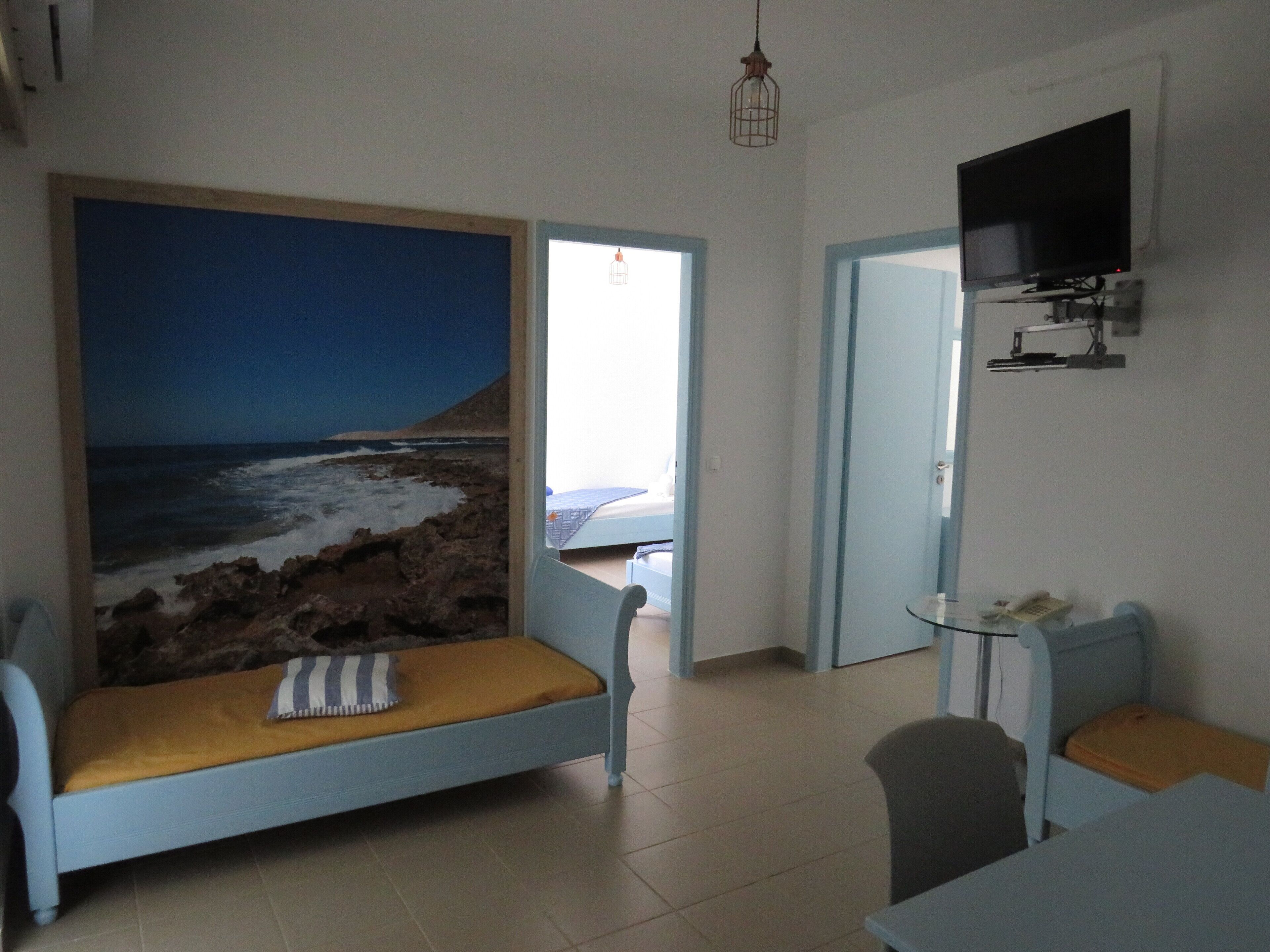 Una habitación con cama, televisor montado en la pared y vista al mar a través de un ventanal grande.