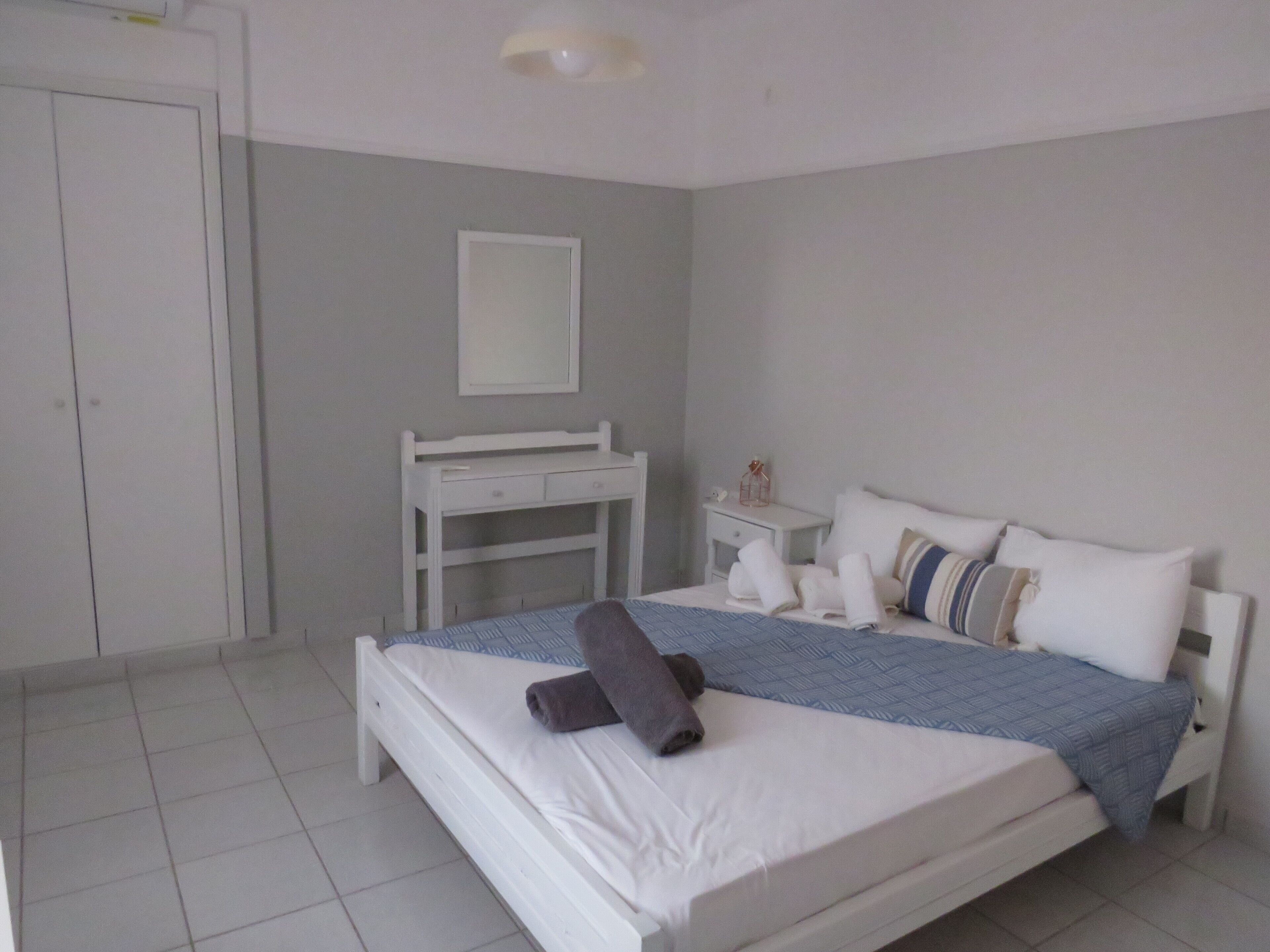 Un dormitorio con cama, escritorio, silla y mesita de noche.