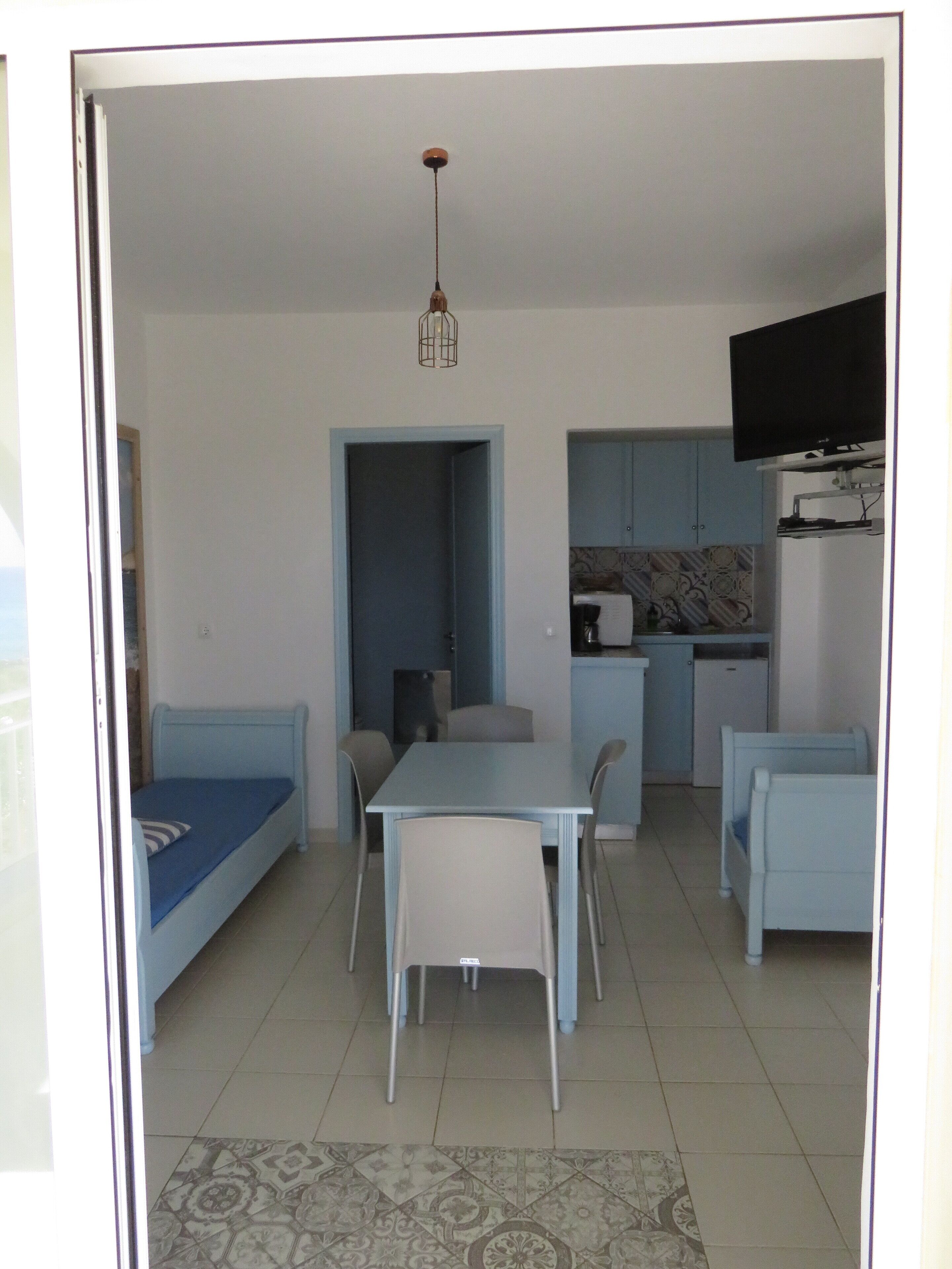 Un espacio habitable compacto con comedor, kitchenette y un dormitorio pequeño.
