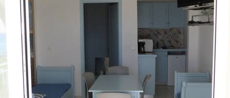 Un espacio habitable compacto con comedor, kitchenette y un dormitorio pequeño.