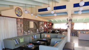 Een ruime woonkamer met een grote hoekbank, een bijzettafeltje en een boekenplank vol boeken.