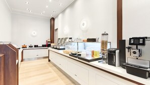 Ein moderner Küchenbereich mit Kaffeestation, Speisenauslage und Getränkespender.