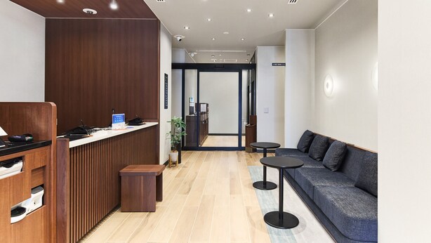 Ein Empfangsbereich mit einem Holzbüro, einer Couch und einem kleinen Tisch.