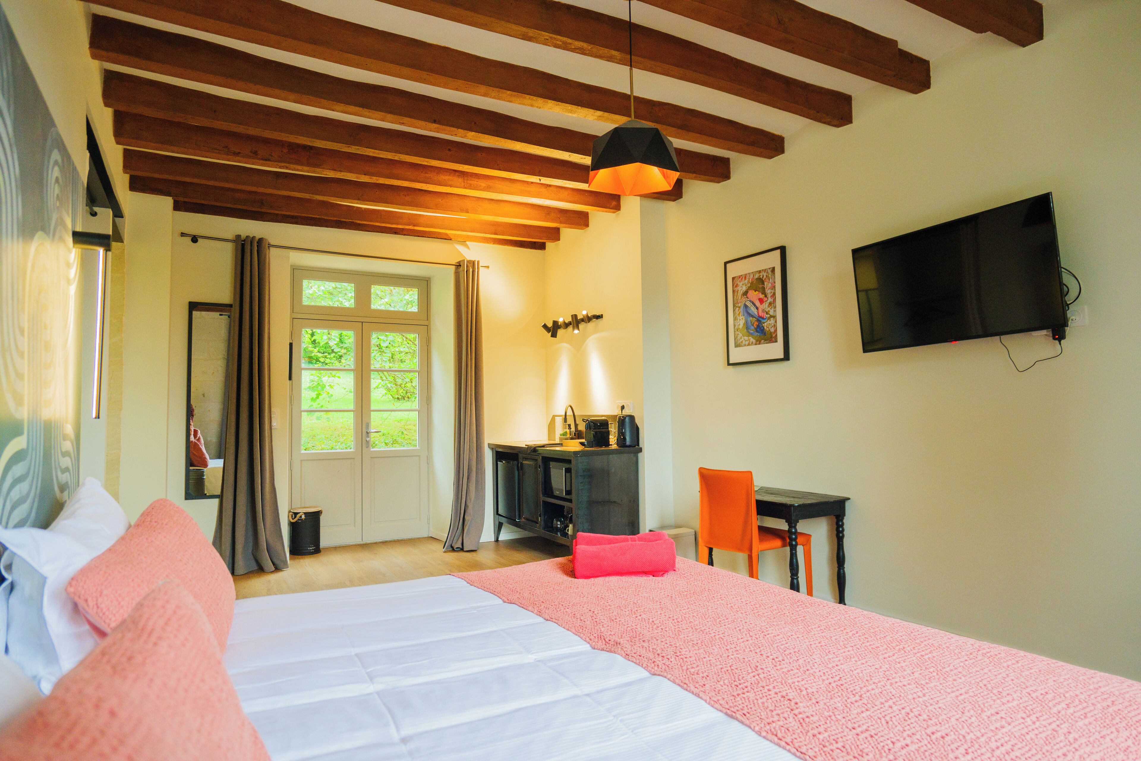 A bedroom with a bed, a desk, a chair, a TV, and a window with curtains.