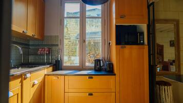 Una cocina con armarios de madera, una ventana con vista a un muro de piedra y un microondas en la encimera.