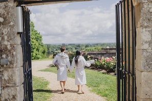 A pathway leading through an open gate, surrounded by greenery and a stone wall. - Château de Candes Art et Spa (Candes-Saint-Martin)