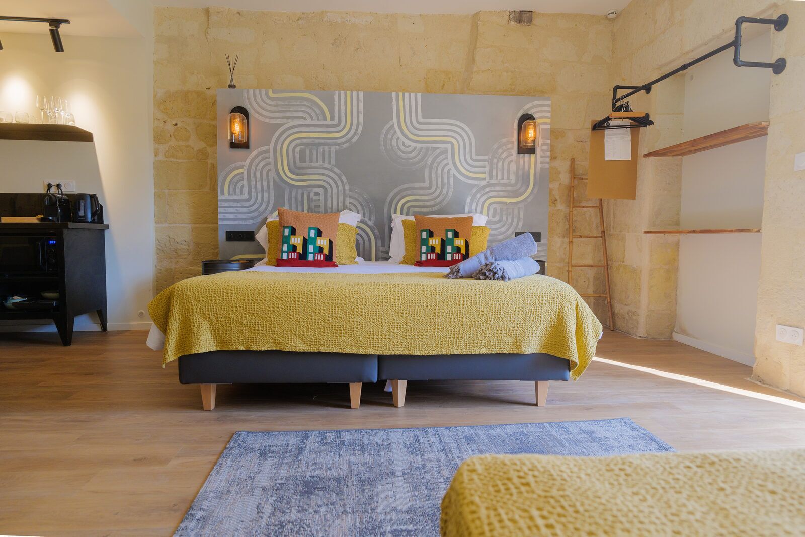 Un dormitorio con una cama, una mesita de noche, una lámpara y una pared con diseño decorativo.