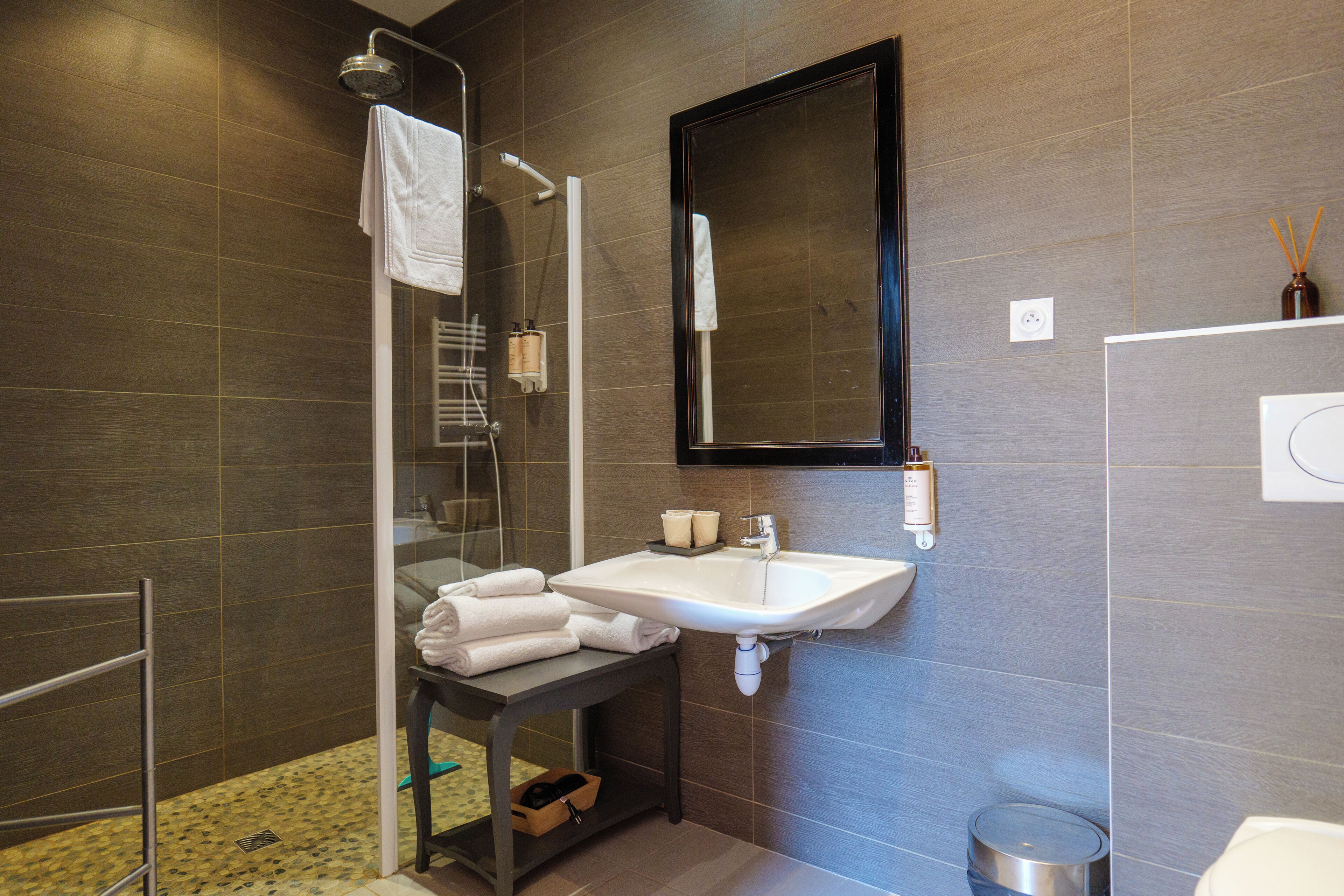 Une salle de bain moderne avec une douche à parois de verre, un lavabo blanc et un miroir.