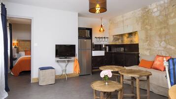 A compact living space with a kitchenette, a dining area with a round table, and a sofa with cushions.