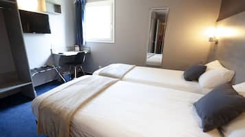 Habitación de hotel con dos camas, un escritorio, una silla, un televisor y una ventana con cortinas.