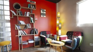 A cozy reading nook with a bookshelf, a colorful armchair, and a small table.