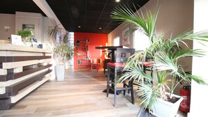 A modern interior with wooden flooring, a red accent wall, and multiple potted plants.