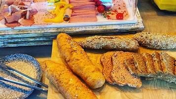 A variety of breads and cured meats on a wooden table.