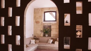 A cozy room with a stone wall, a wooden bench, and a window with a view of a staircase. - B&B Masseria 12 Granai (Minervino di Lecce)