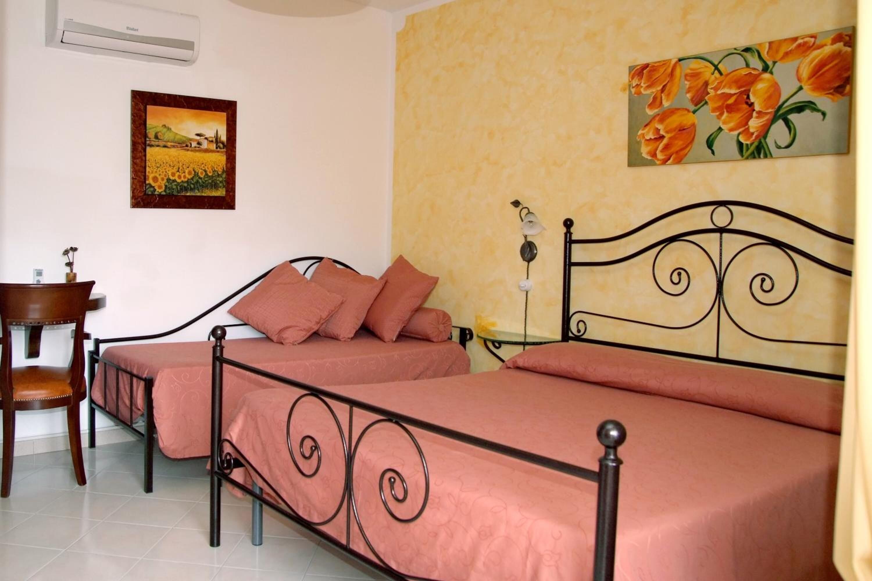 Une chambre avec deux lits simples, une chaise en bois, une petite table et un climatiseur fixé au mur.