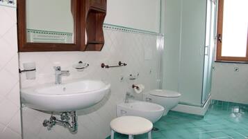 Une salle de bain avec un grand lavabo, un plus petit lavabo, des toilettes et une douche.
