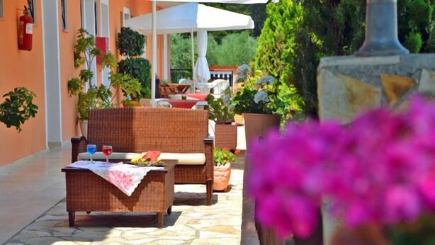 Un'area patio esterna con mobili in vimini, piante in vaso e pavimento in pietra.