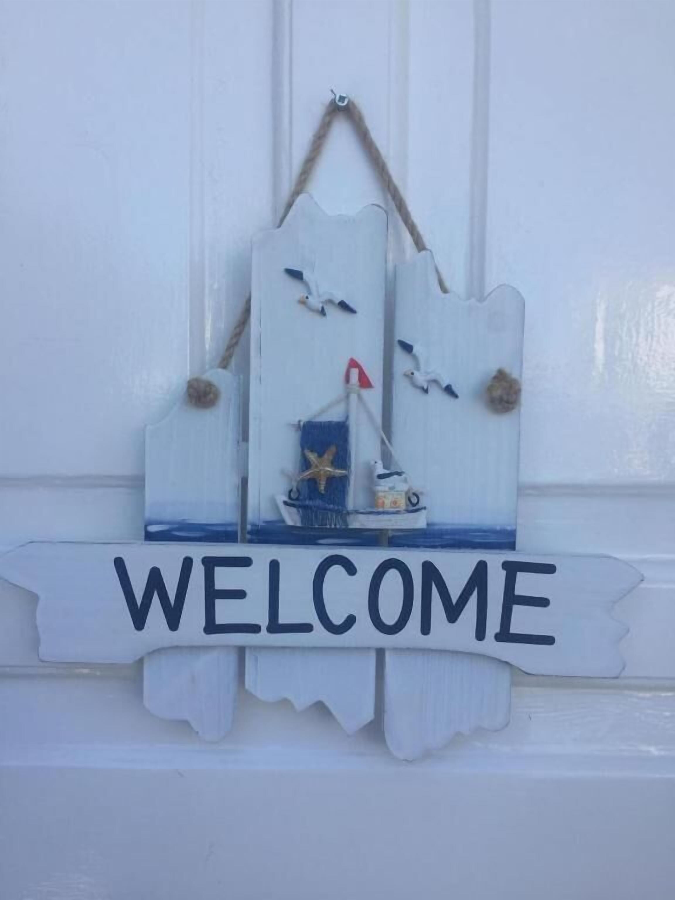 A welcome sign with a sailboat and seagulls.