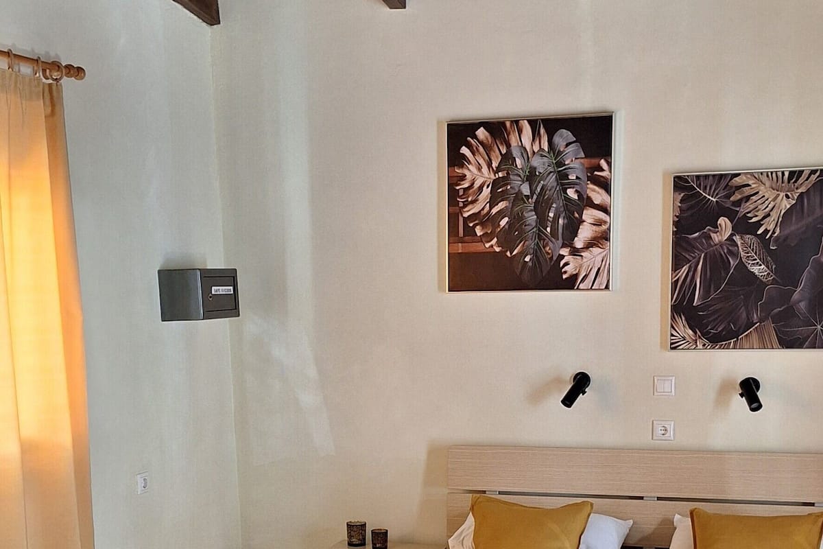 A hotel room with a bed, two wall-mounted nightstands, a ceiling fan, and two framed artworks.