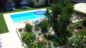Una piscina rodeada por un jardín con diversas plantas y flores.