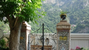 A gated entrance with a decorative iron gate, stone pillars, and a sign indicating Villa Polumbo. - Villa Palumbo (Positano)