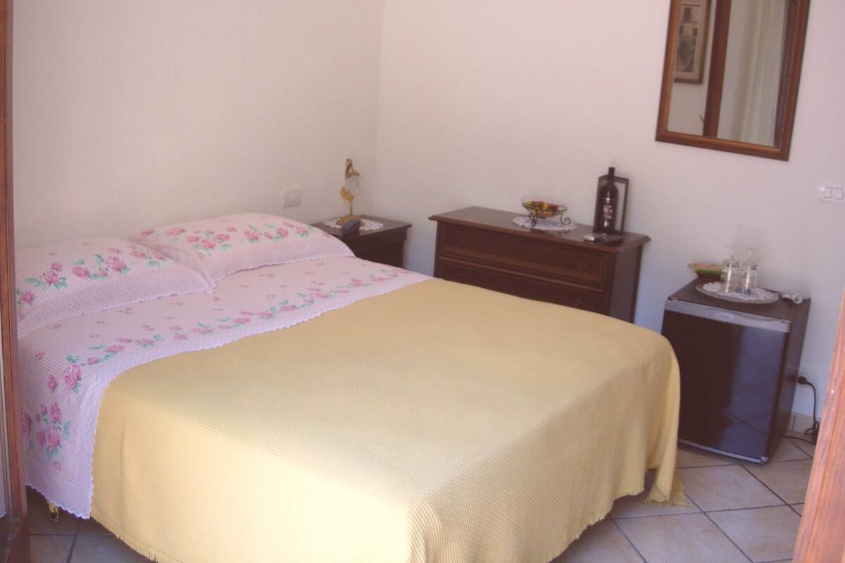 Une chambre à coucher avec un lit, une table de chevet, une commode et un miroir.