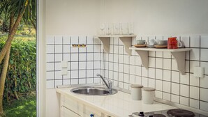 Una cocina con un lavamanos, estufa y repisas sobre la encimera.