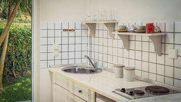 A kitchen with a sink, stove, and shelves above the countertop.