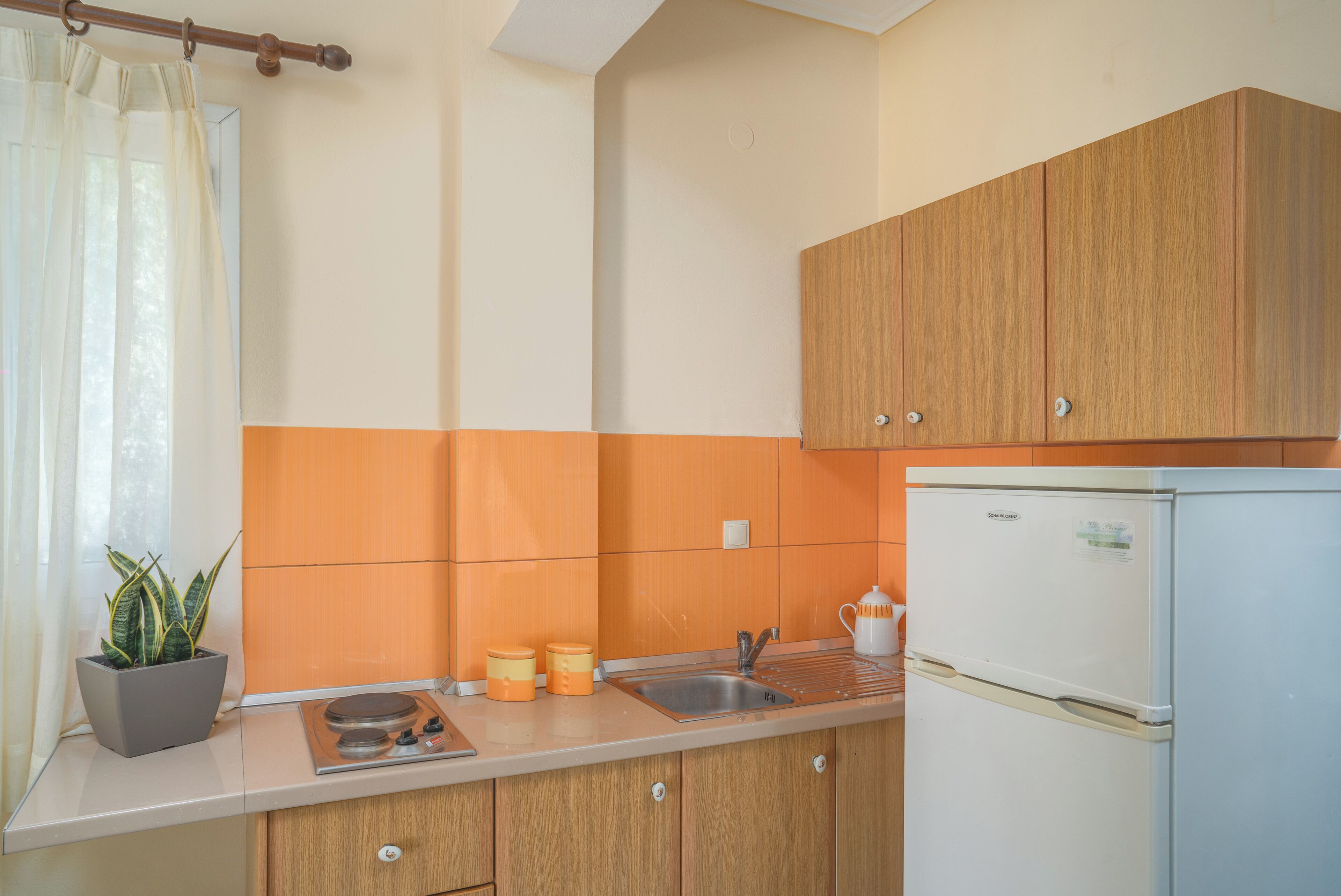 A kitchen with wooden cabinets, a sink, a stove, and a refrigerator.
