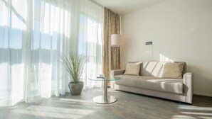 A modern living room with a sofa, a glass table, and a potted plant. - Hotel Swiss Star (Wetzikon)
