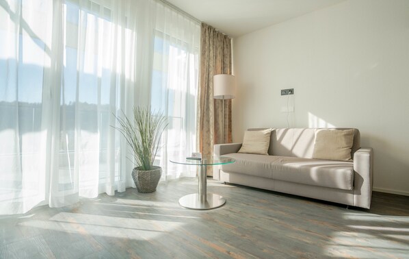 Una sala de estar moderna con un sofá, una mesa de vidrio y una planta en maceta.
