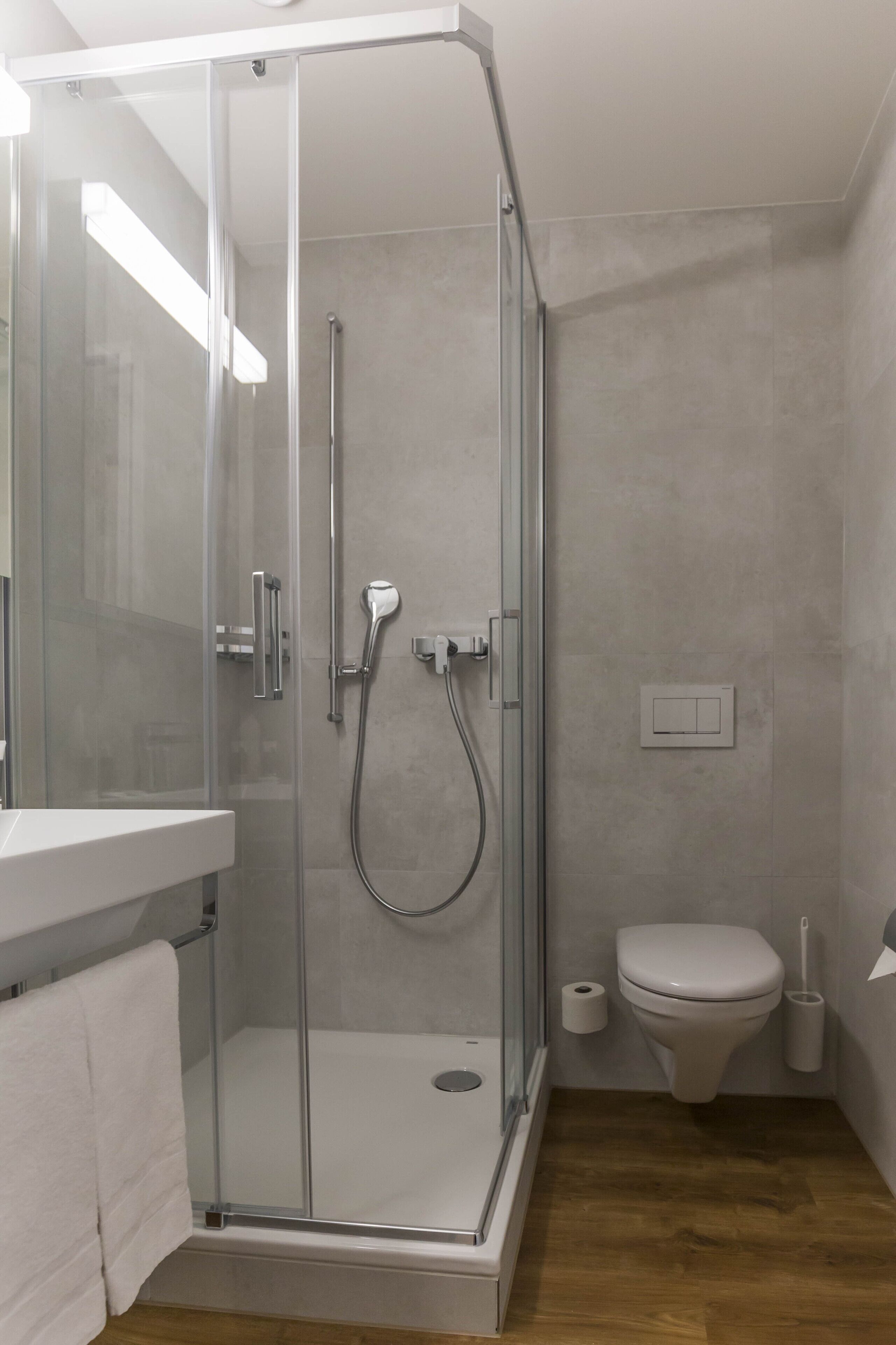 Ein modernes Badezimmer mit einer begehbaren Glasdusche, einer Toilette und einem Waschbecken mit einem Handtuch.