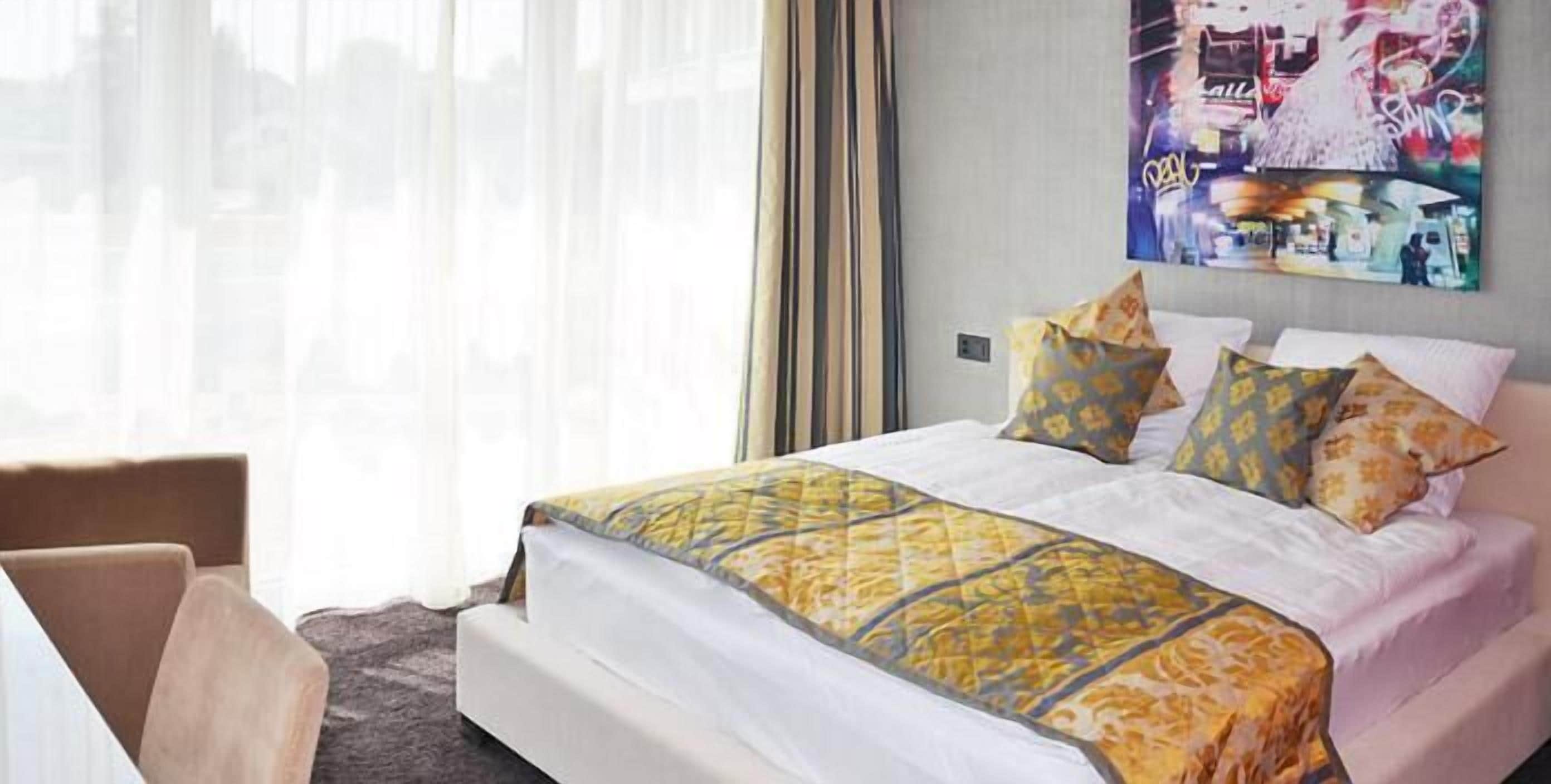 Ein Hotelzimmer mit einem großen Bett, einem Sessel und einem Bild an der Wand.