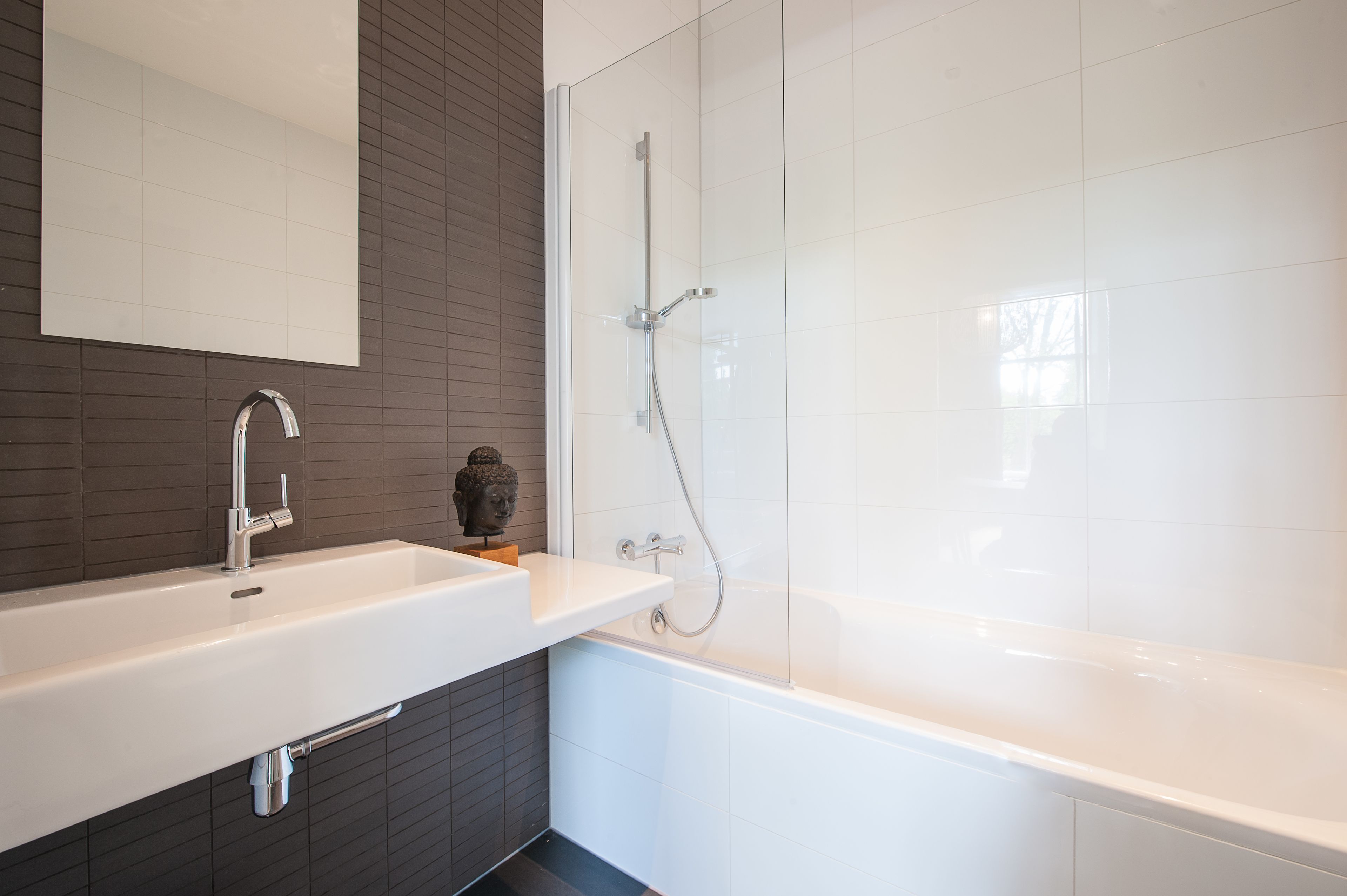 A modern bathroom with a white sink, a mirror, and a shower.