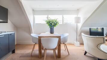 Een moderne eetruimte met een houten tafel, witte stoelen en een potplant.
