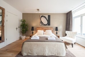 Une chambre moderne avec un grand lit, une plante en pot et une vue sur la ville.