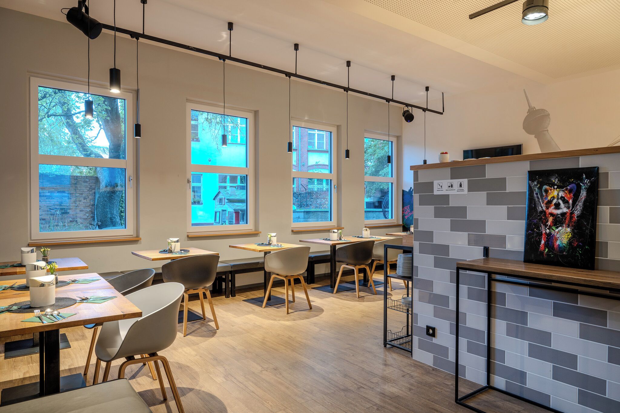 A modern restaurant with large windows, wooden tables, and chairs.