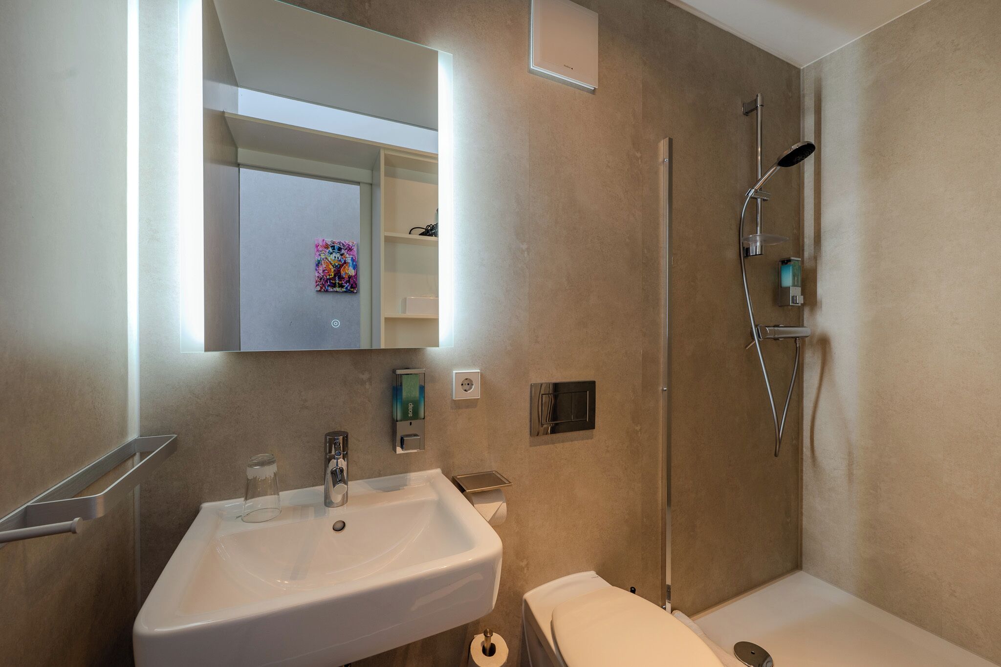 Un baño moderno con lavamanos, inodoro y ducha.