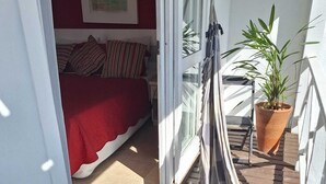 A balcony with a hammock, a potted plant, and a bed with striped bedding. - Pousada Mar de Búzios (Búzios)