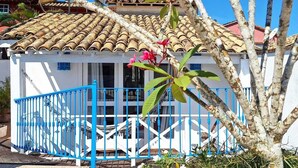 A building with a tiled roof, a blue gate, and a wooden deck. - Pousada Mar de Búzios (Búzios)