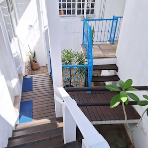 A staircase with blue railings leading to a landing, surrounded by white walls and potted plants. - Pousada Mar de Búzios (Búzios)