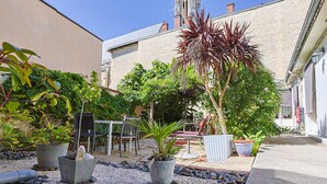 Un patio con macetas, una zona de estar y un edificio de paredes de piedra.