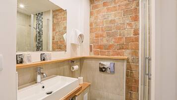 A bathroom with a large white sink, a mirror, and a shower area.