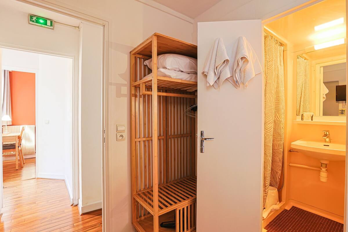 A hotel room with a wooden wardrobe, a bathroom with a zebra-patterned shower curtain, and a sink.