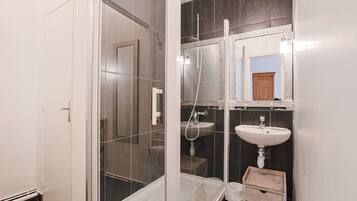 Un baño con cabina de ducha de vidrio, un lavabo y un espejo.
