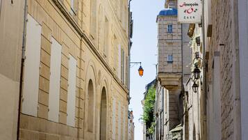 Eine schmale Straße mit historischen Gebäuden, einem Schild für „HOTEL Francois d'O CAEN“ und traditionellen Straßenlaternen.