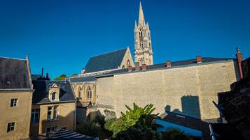 A historic building with a prominent tower and a courtyard with stone walls and greenery.