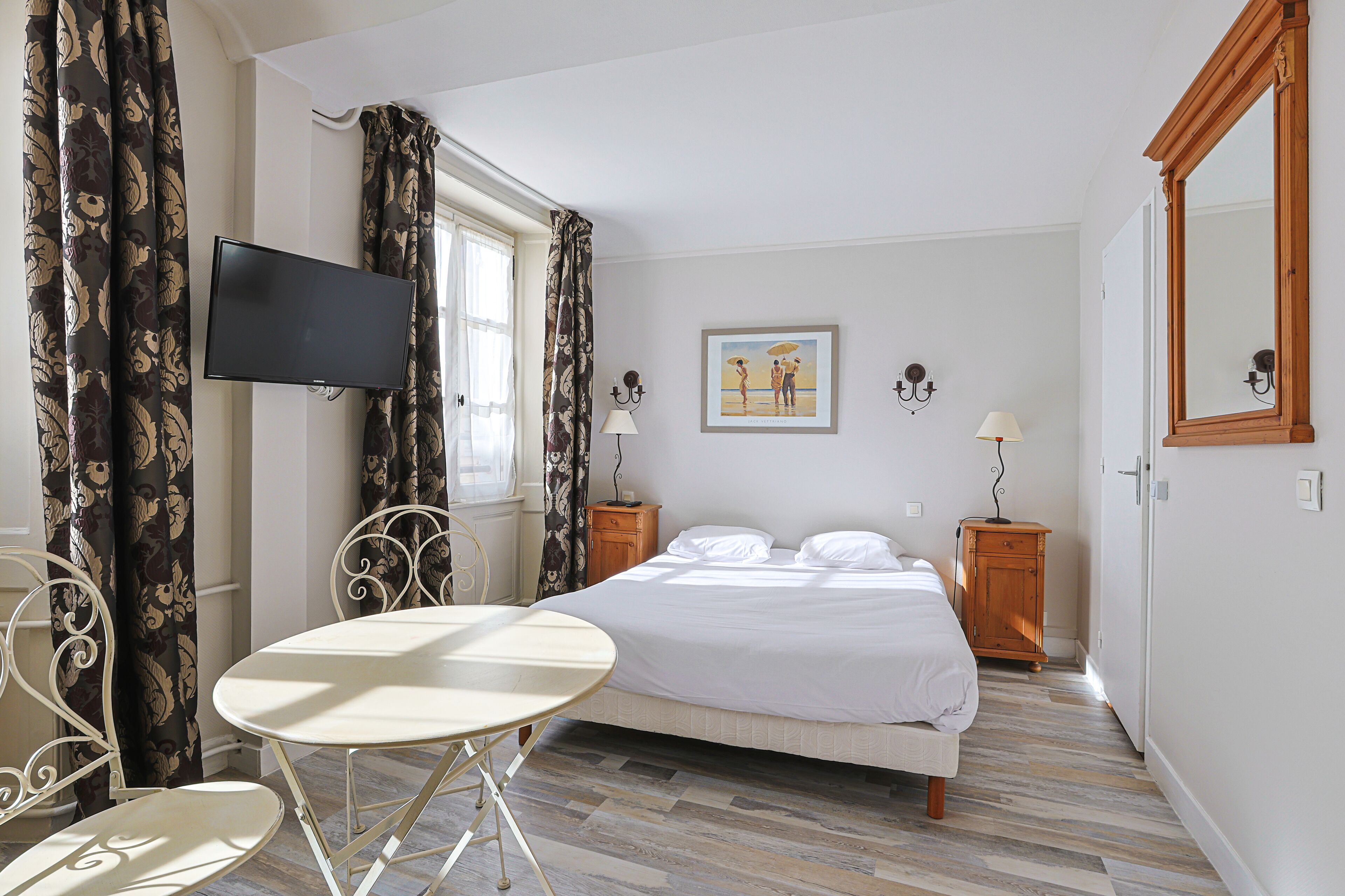Un dormitorio con cama, televisor, mesa y silla.